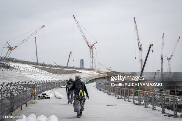 This photo taken on April 2, 2024 shows workers walking at the construction site of the "Grand Roof", known as the Ring, one of the world's largest...