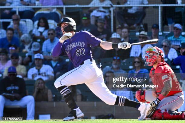 Aaron Schunk of the Colorado Rockies hits a double during the eighth inning of a spring training game against the Cincinnati Reds at Salt River...