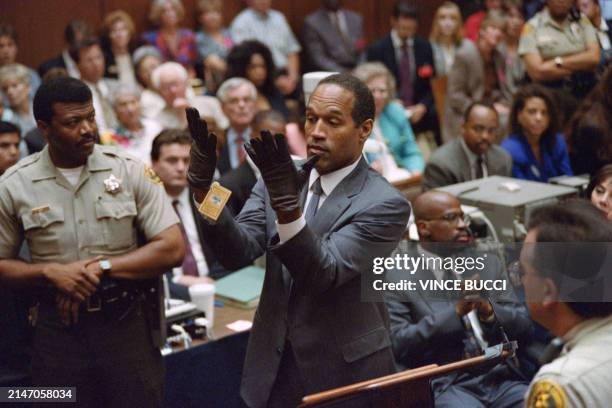 Double murder defendent O.J. Simpson , looks at a new pair of Aris extra-large gloves which the prosecutors had him put on for the jury on June 21,...