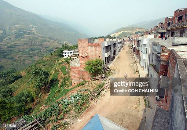 The main street in the centre of the new migrant village of Guihua, with the state-built houses tediously identical, lined one after another,...