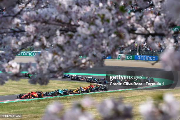 Carlos Sainz of Spain driving the Ferrari SF-24 leads Fernando Alonso of Spain driving the Aston Martin AMR24 Mercedes after a restart following a...
