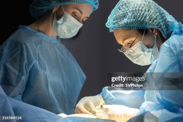 the plastic surgeon and the surgical nurse perform an operation. - plastic surgeon stock pictures, royalty-free photos & images