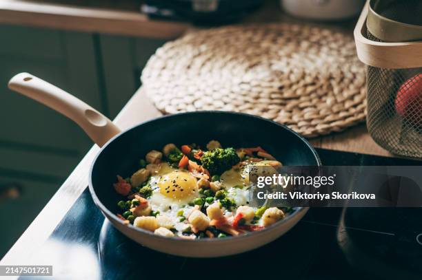 closeup of fried eggs and vegetables in a frying pan. - spinach frittata stock pictures, royalty-free photos & images