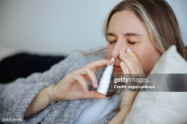 sick young woman using nasal spray - neusspray stockfoto's en -beelden