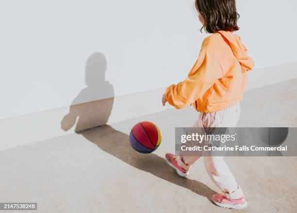 simple image of a child retrieving a colourful basketball - linebacker stock pictures, royalty-free photos & images