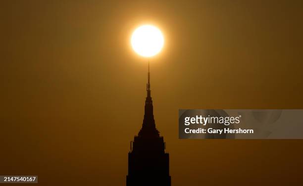 The sun rises behind the Empire State Building on the day of the solar eclipse in New York City on April 8 as seen from Jersey City, New Jersey.