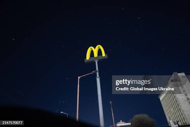 Pylon with the McDonald’s logo stands in front of a starry sky next to unlit streetlights without electricity due to Russian shelling on April 7,...