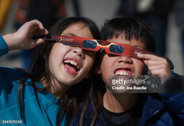 Miriam Toy and Oliver Toy share a pair of eclipse glasses that NASA was handing out as they await the eclipse on April 08 in Houlton, Maine. Millions...
