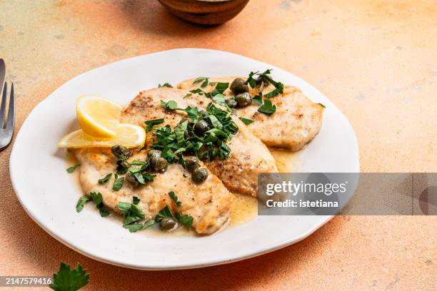 chicken piccata with capers in white plate, traditional italian dish - alimentos cocinados fotografías e imágenes de stock
