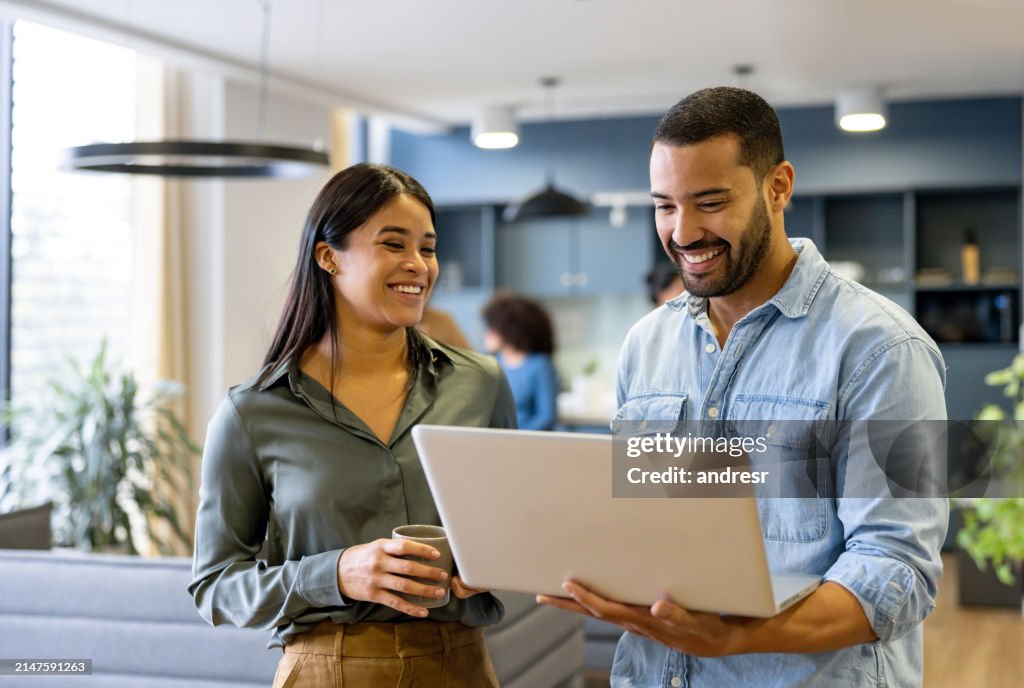 Une équipe d’affaires heureuse travaillant ensemble à l’aide d’un ordinateur portable au bureau et souriante