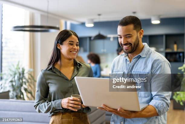 une équipe d’affaires heureuse travaillant ensemble à l’aide d’un ordinateur portable au bureau et souriante - collègue photos et images de collection