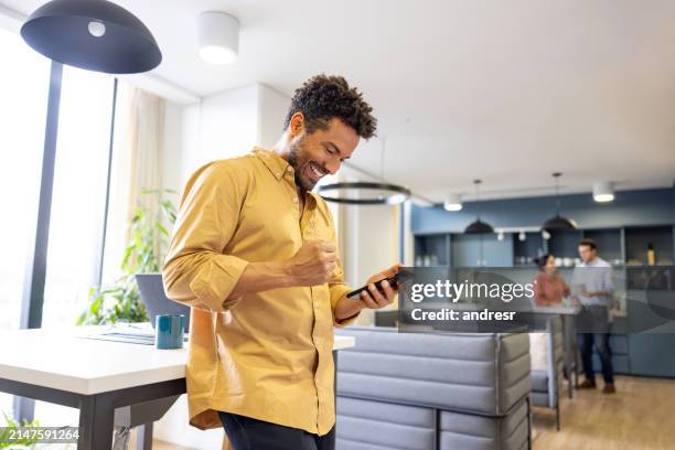 successful businessman receiving good news and celebrating at the office - boa notícia imagens e fotografias de stock