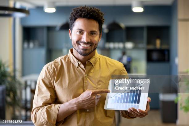 uomo d'affari in ufficio che indica un grafico di crescita su una tavoletta digitale - crescita foto e immagini stock