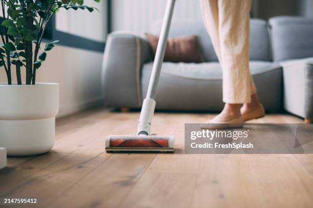 persona che pulisce il pavimento in legno con un aspirapolvere moderno - aspirapolvere foto e immagini stock