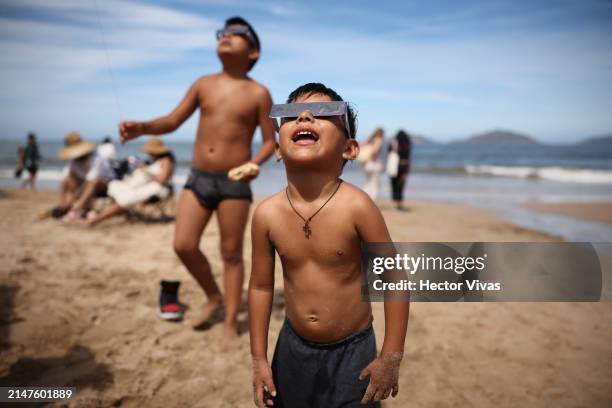 Kid watches the eclipse from the beach on April 08, 2024 in Mazatlan, Mexico. Millions of people have flocked to areas across North America that are...