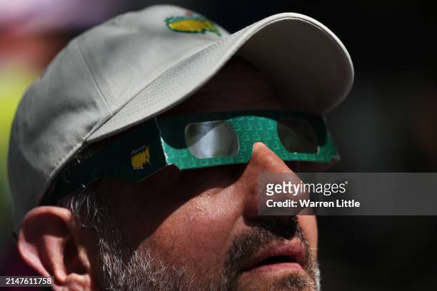 Patron uses glasses to view the eclipse during a practice round prior to the 2024 Masters Tournament at Augusta National Golf Club on April 08, 2024...