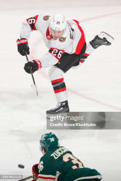 Erik Brannstrom of the Ottawa Senators passes the puck with Mats Zuccarello of the Minnesota Wild defending during the game at the Xcel Energy Center...