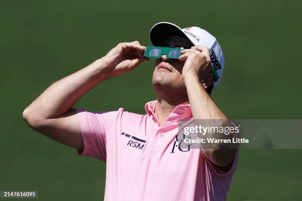 Zach Johnson of the United States uses glasses to view the eclipse during a practice round prior to the 2024 Masters Tournament at Augusta National...