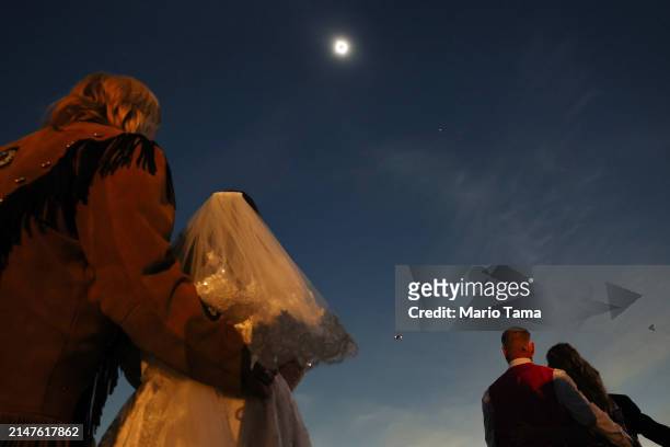 Couples view the solar eclipse during totality at a mass wedding at the Total Eclipse of the Heart festival on April 8, 2024 in Russellville,...