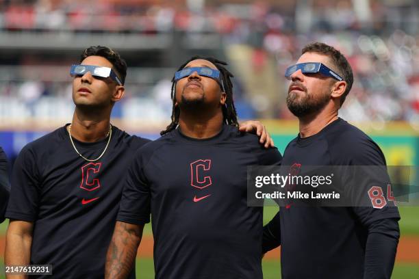 Brayan Rocchio, José Ramírez and J.T. Maguire of the Cleveland Guardians look up at the total solar eclipse before the home opener against the...