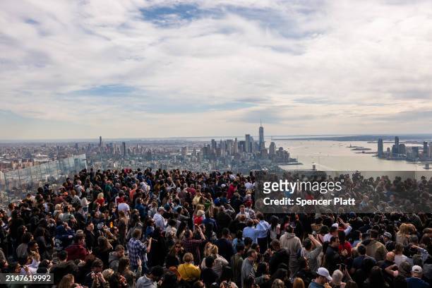 People watch a partial solar eclipse on the observation deck of Edge at Hudson Yards on April 08, 2024 in New York City. While New York City isn't in...