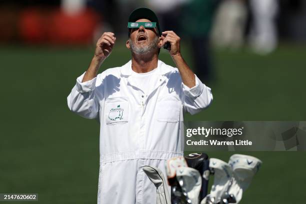 Caddie uses glasses to view the eclipse during a practice round prior to the 2024 Masters Tournament at Augusta National Golf Club on April 08, 2024...