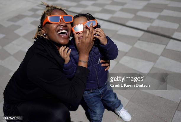 Woman and child take in the partial solar eclipse outside of the Fiserv Forum on April 08, 2024 in Milwaukee, Wisconsin. Millions of people have...