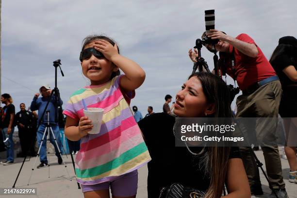 Girl looks to the sky using special glasses to watch the eclipse at Cristo de Las Noas on April 08, 2024 in Torreon, Mexico. Millions of people have...