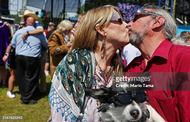 Couple kisses while holding a dog during a mass wedding at the Total Eclipse of the Heart solar eclipse festival on April 8, 2024 in Russellville,...
