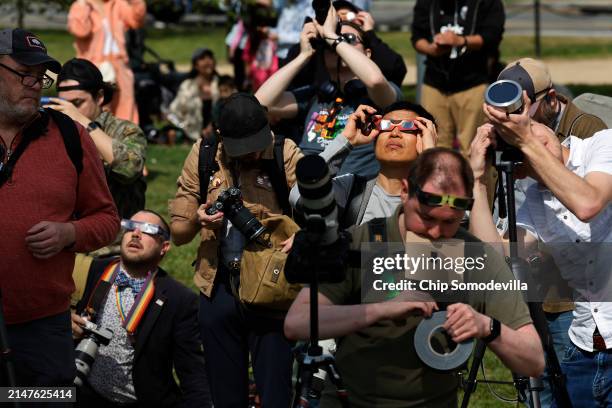 Photographers capture the solar eclipse near the base of the Washington Monument on the National Mall on April 08, 2024 in Washington, DC. People...