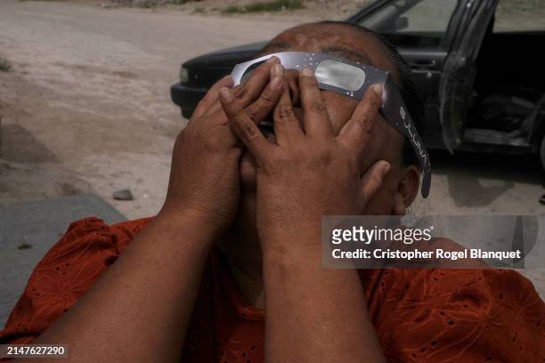 Woman watches the eclipse using special glasses on April 8, 2024 in 22 de Febrero, Mexico. Millions of people have flocked to areas across North...