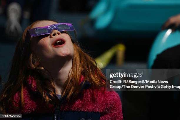 Nine-year-old Bryn Hill and other fourth graders from STEM School Highlands Ranch watch the solar eclipse at Littles Creek Park during a field trip...