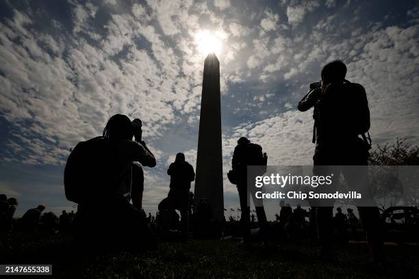 Photographers capture the solar eclipse near the base of the Washington Monument on the National Mall on April 08, 2024 in Washington, DC. People...