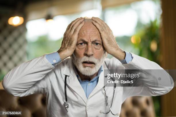 portrait of shocked senior doctor looking at camera in his office. - flatten the curve imagens e fotografias de stock