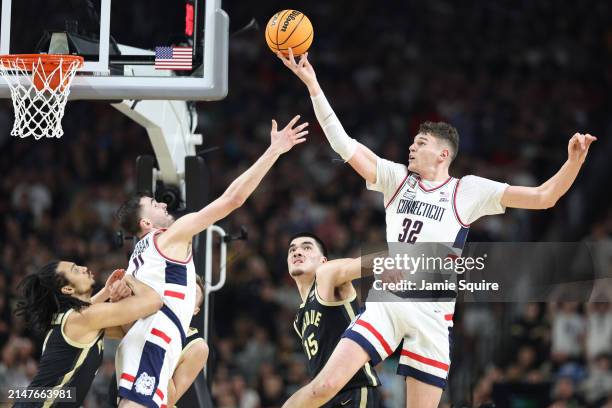 Donovan Clingan of the Connecticut Huskies attempts a shot while being guarded by Zach Edey of the Purdue Boilermakers in the second half during the...