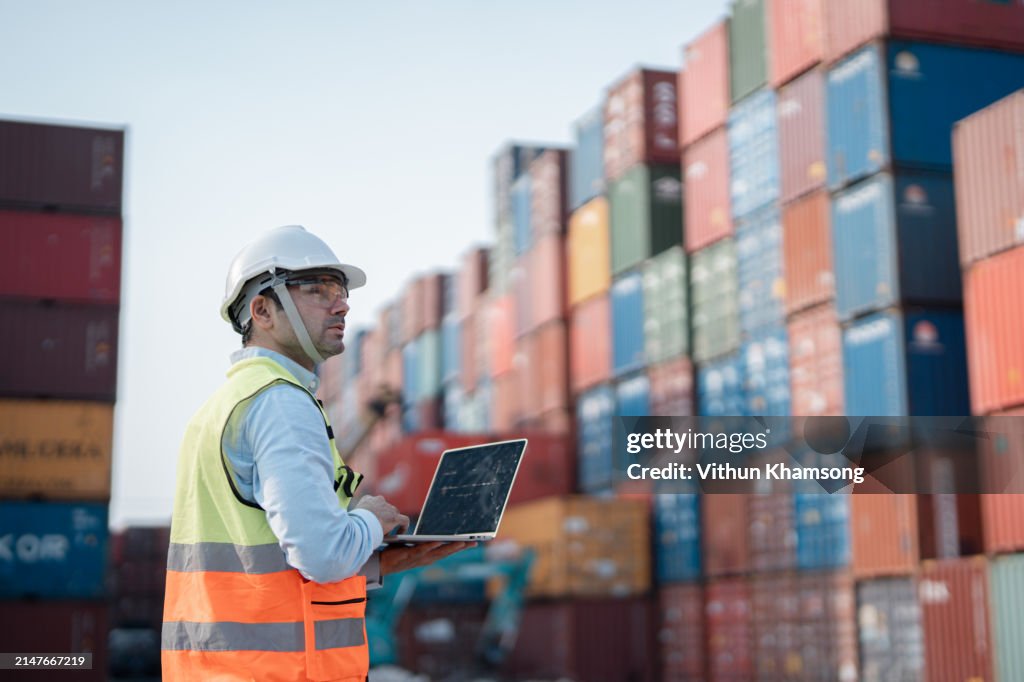 Male engineer working at Containers yard. Cargo port storage for transportation and trading.