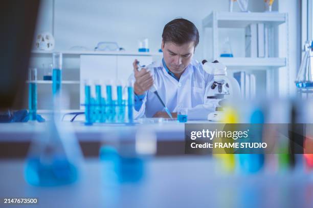 focused scientist using a pipette in a laboratory setting with equipment and a microscope on the bench. - faculty development stock pictures, royalty-free photos & images
