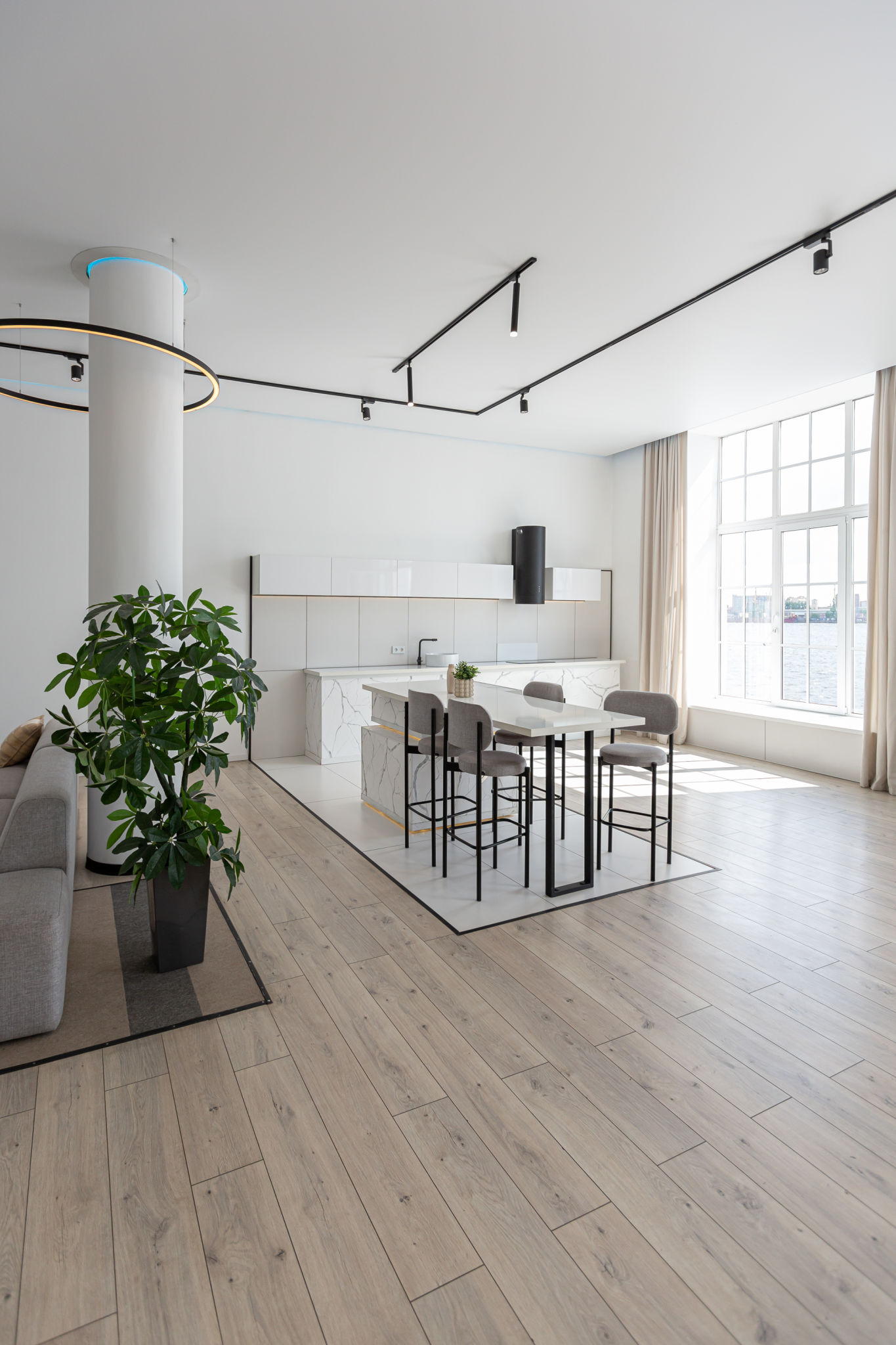 kitchen and dining island with high bar stools in a minimalistic modern luxury design of an expensive house on a sunny day. white walls with plaster, parquet, decorative lighting and no one inside kitchen and dining island with high bar stools in a minimalistic modern luxury design of an expensive house on a sunny day. white walls with plaster, parquet, decorative lighting and no one inside