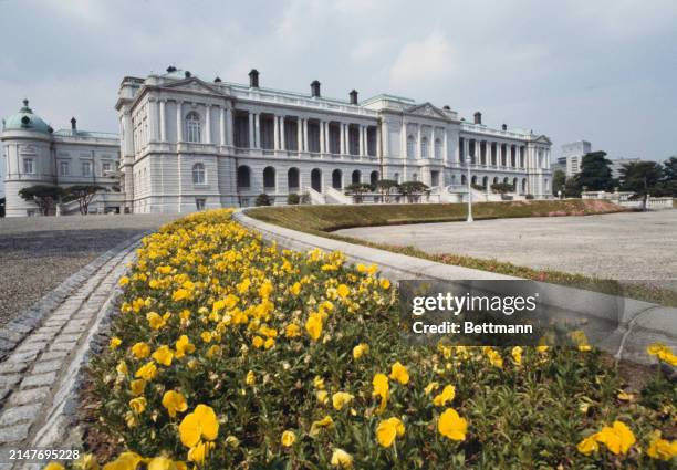 Exterior view of the Akasaka Palace, now a state guest house of the government of Japan, with a bed of yellow pansies in the foreground, Tokyo, May...