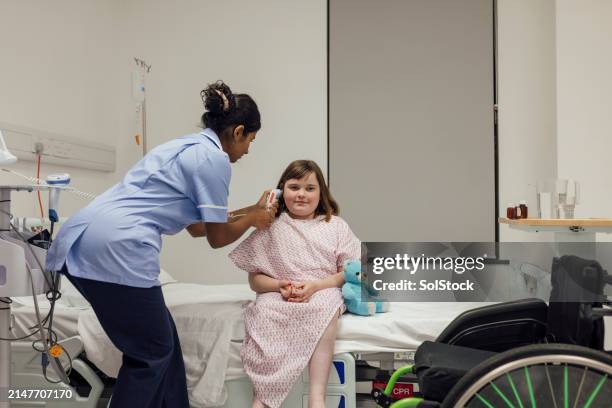 nurse taking young girl's temperature - exam preparation stock pictures, royalty-free photos & images