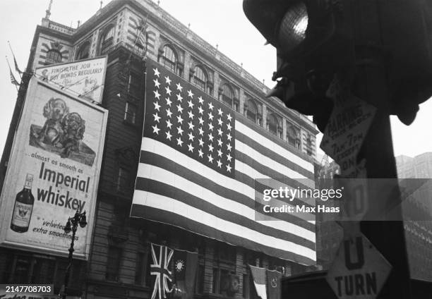 Huge American flag unfurled from the eighth floor balcony of Macy's New York department store near Herald Square on VE-Day, US, 8th May 1945; beneath...