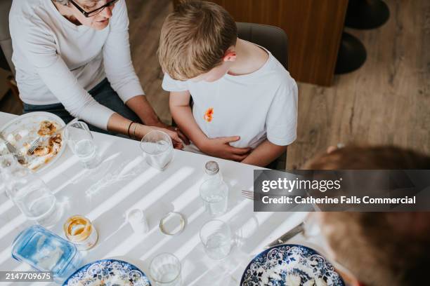 a grandmother fusses over her grandson who has just stained his white t-shirt - prueba de tinción fotografías e imágenes de stock