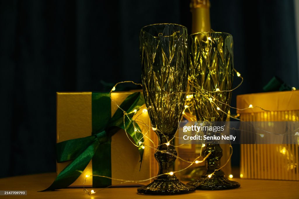 Green glasses and New Year's gift with Christmas garland on the table close-up