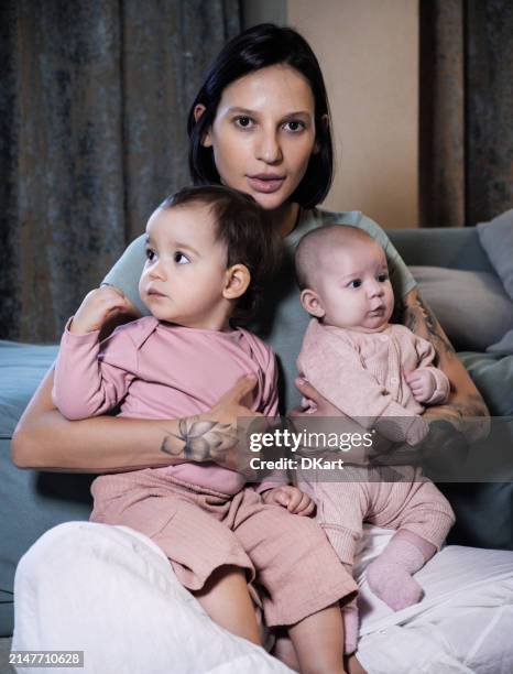 young pretty mother and her infant daughters watching movie at home - arab people stock pictures, royalty-free photos & images