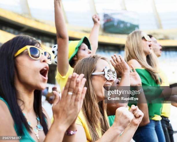 sports fans: soccer supporters cheering in the crowd at a stadium - voetbalcompetitie sportevenement stockfoto's en -beelden