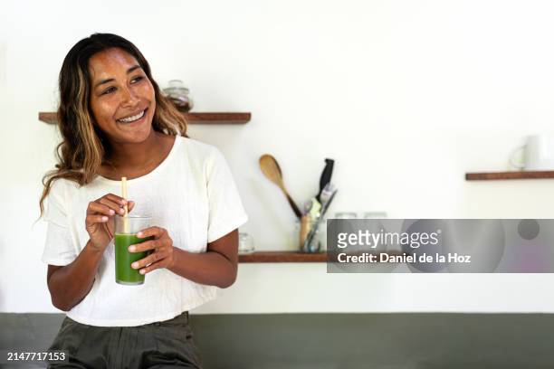 happy young filipino asian woman drinking healthy green juice with bamboo straw. copy space. - stoffwechsel entgiftung stock-fotos und bilder