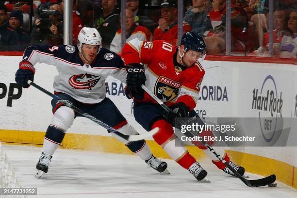 Vladimir Tarasenko of the Florida Panthers digs the puck out from the boards against Cole Sillinger of the Columbus Blue Jackets at the Amerant Bank...