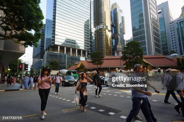 Pedestrians pass commercial buildings in the central business district in Singapore, on Thursday, April 11, 2024. Singapore's central bank kept its...
