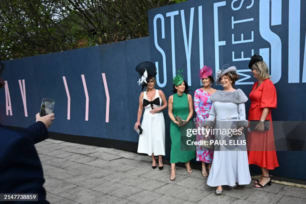 Racegoers pose for a photograph as they attend on Ladies Day, the second day of the Grand National Festival horse race meeting at Aintree Racecourse...