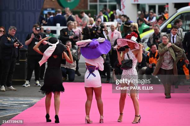Racegoers pose for a photograph as they attend on Ladies Day, the second day of the Grand National Festival horse race meeting at Aintree Racecourse...